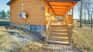 Une cabane en bois dotée d’un porche couvert et d’un escalier menant à un étage supérieur.