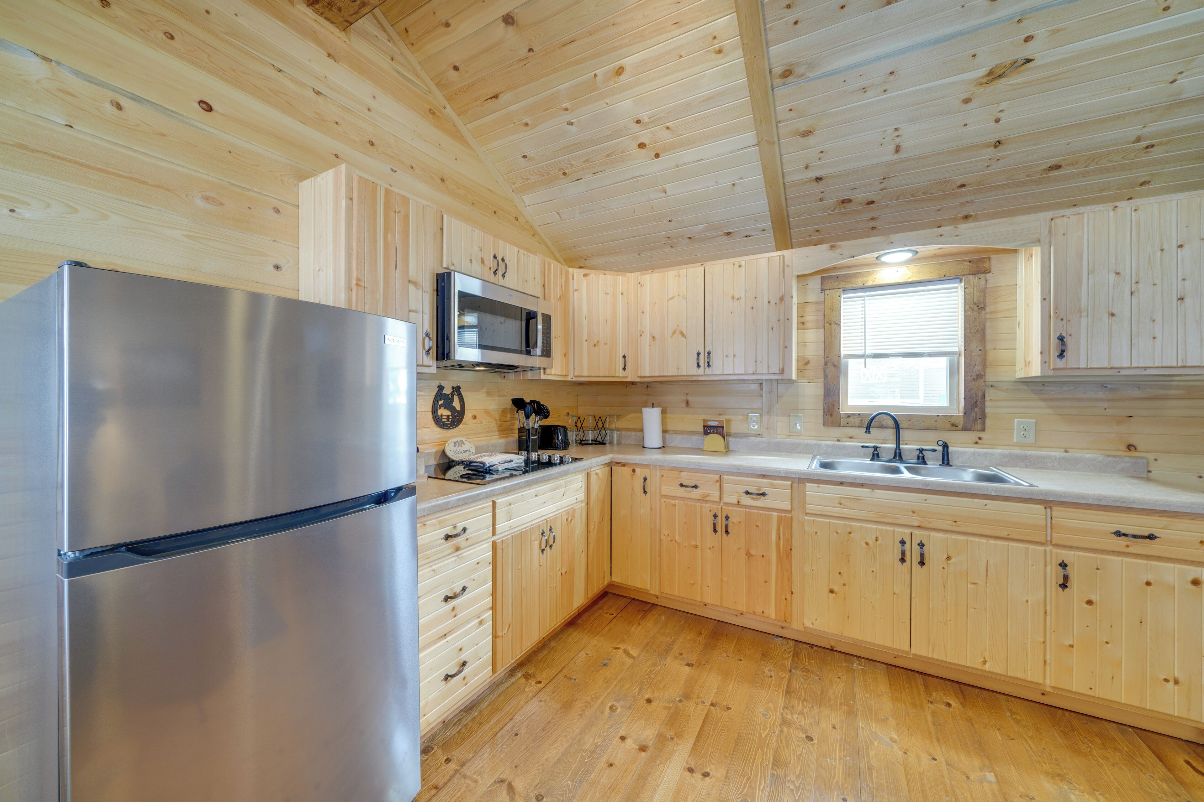 A modern kitchen with wooden cabinets, a stainless steel refrigerator, a microwave, and a sink.