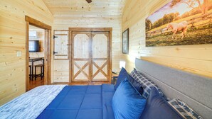 Una camera in una baita di legno con un letto, una ventola a soffitto e un quadro di un cavallo.
