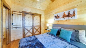 A wooden room with a bed, a painting of horses, and a door. - 31 Mi to Louisville: Cabin on 235 Acres! (La Grange)