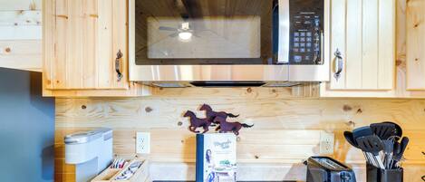 A kitchen with wooden cabinets, a microwave, a toaster, and a coffee machine.