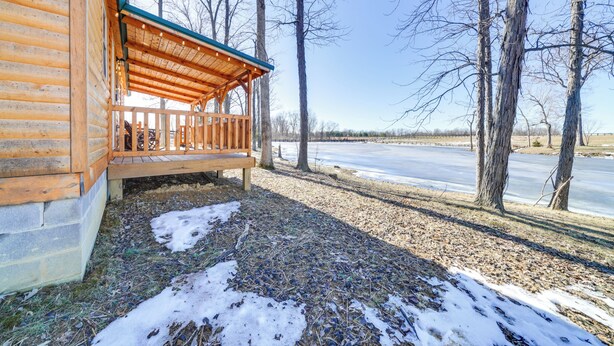 A wooden cabin with a porch and a view of a frozen lake. - 31 Mi to Louisville: Cabin on 235 Acres! (La Grange)