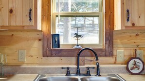 A kitchen with wooden cabinetry, a double sink, and a window with a decorative horse silhouette. - 31 Mi to Louisville: Cabin on 235 Acres! (La Grange)