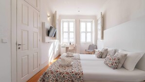 Een hotelkamer met een bed, een bureau, een stoel en een televisie aan de muur.