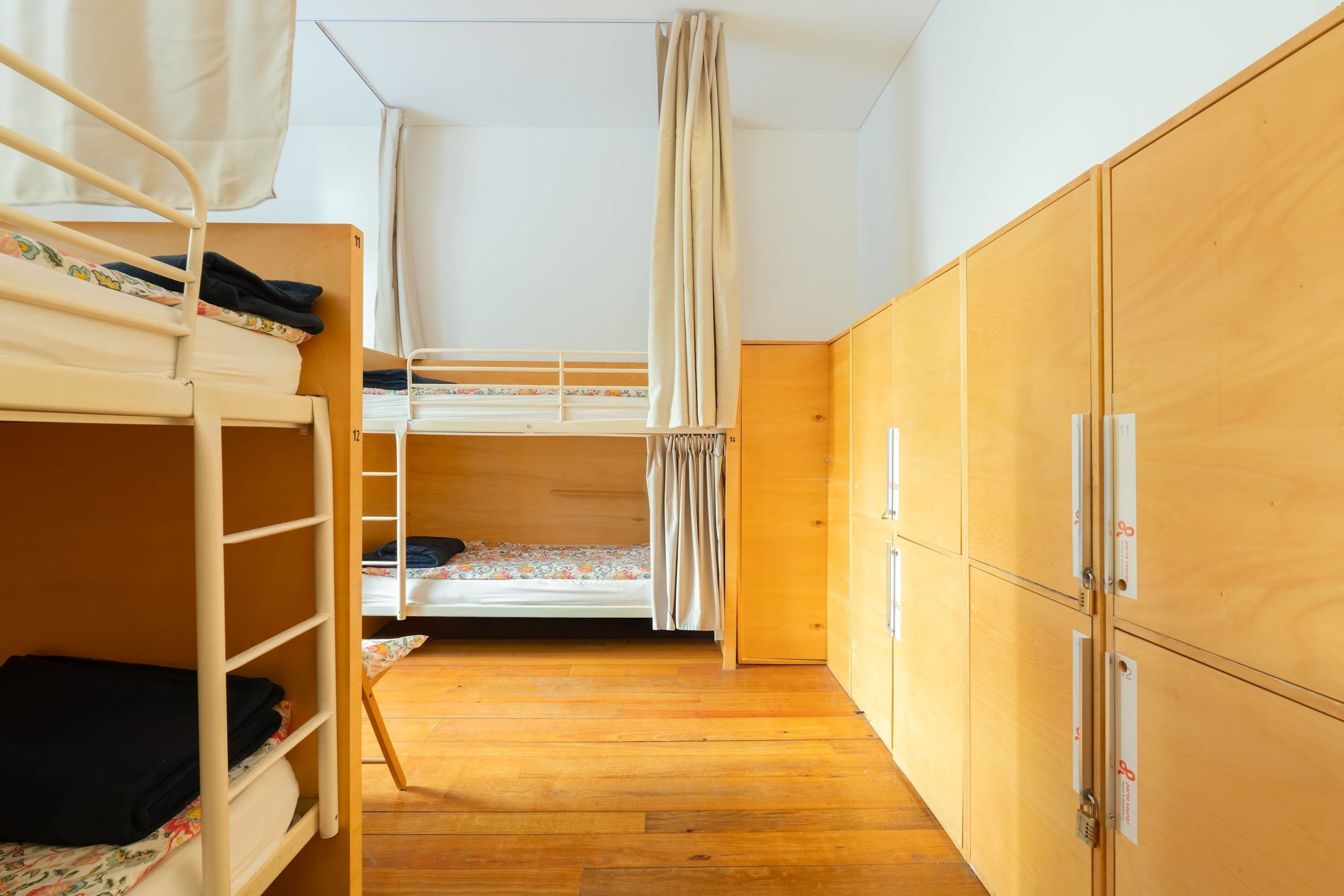 A dormitory room with bunk beds, wooden wardrobe, and a ladder.