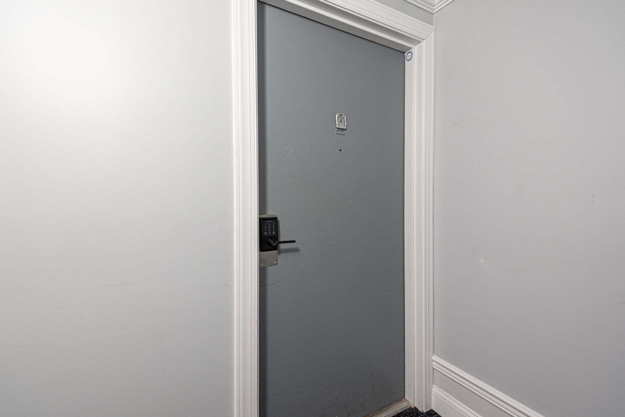A closed door with a keypad lock, a small label, and a vent at the bottom.