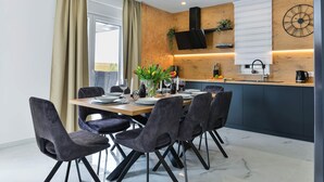 Ein moderner Essbereich mit einem Holztisch, dunklen Stühlen und einer Küche im Hintergrund.