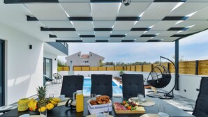 Ein Esstisch mit Frühstücksangeboten, ein Pool und Sitzmöglichkeiten im Freien.