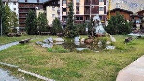 A hotel courtyard with outdoor seating, a small pond, and a rock formation. - Myka Cervinia Apartment - lovely studio apartment in Breuil Cervinia (Breuil-Cervinia)