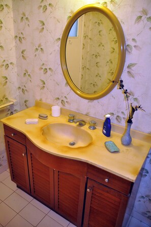 Bathroom features a single sink, a round mirror, and a floral-patterned wall.