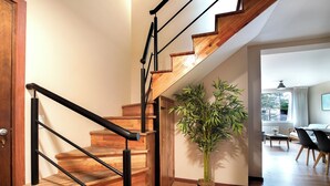 A wooden staircase with black handrails, a potted bamboo plant, and a dining area in the background. - Spacious Central Apartment with Garage (San Carlos de Bariloche)