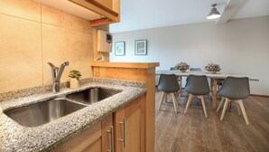 A kitchen with granite countertops, a stainless steel sink, wooden cabinets, and a built-in microwave. - Spacious Central Apartment with Garage (San Carlos de Bariloche)