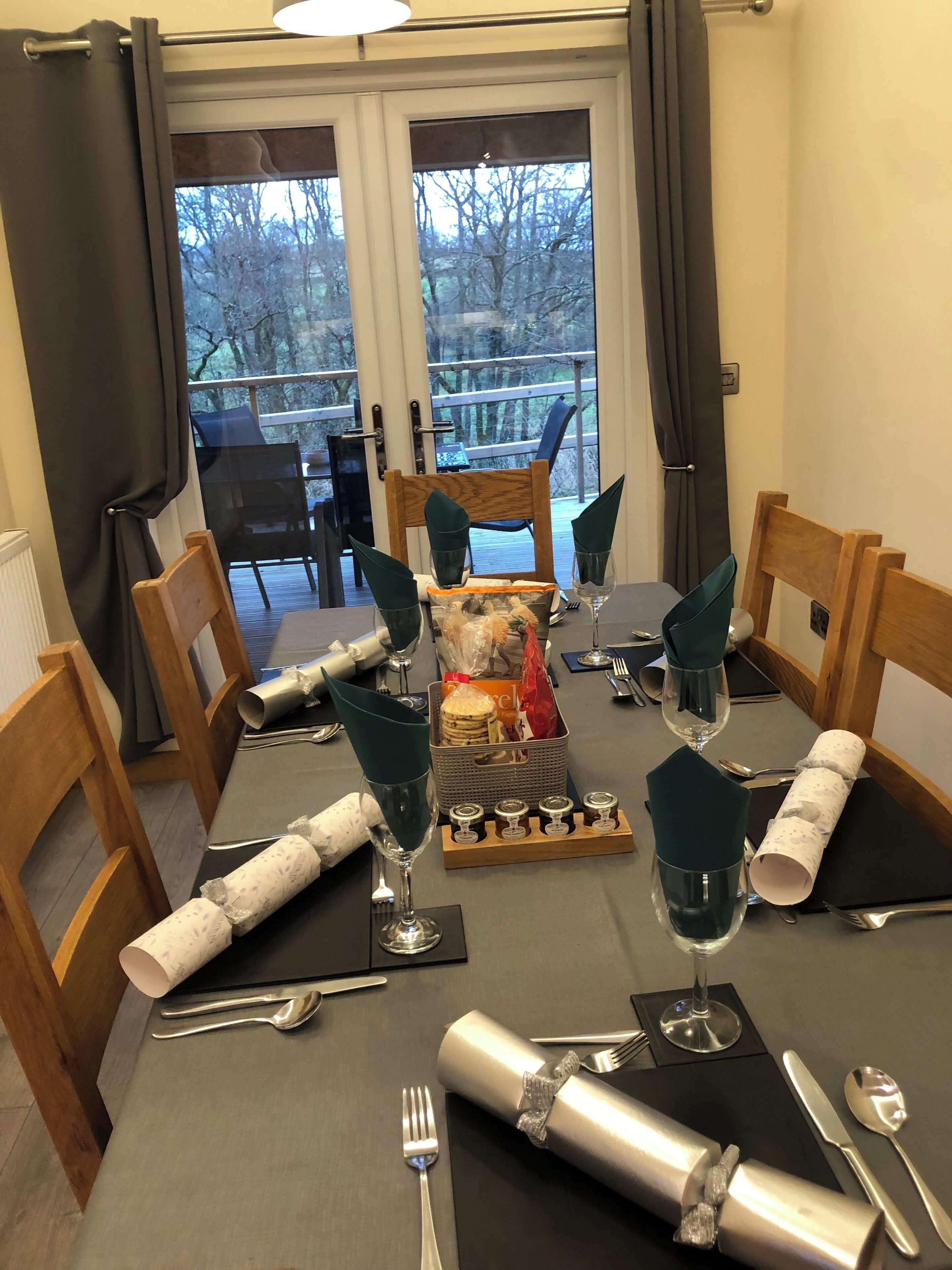 A dining table set for four with a view of a deck and trees.
