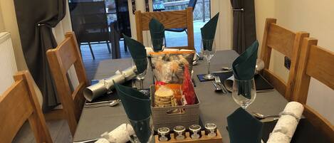A dining table set for four with a view of a deck and trees.