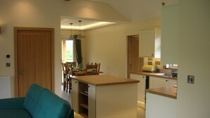 Cocina compacta con comedor, una isla integrada y una zona de estar acogedora con un sofá color turquesa.