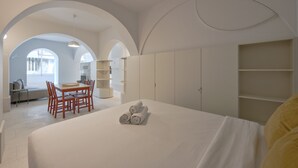Una moderna camera d'albergo con un letto grande, un tavolo da pranzo, sedie, un divano e scaffali a muro.