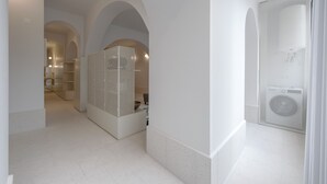 Un interno moderno con pareti bianche, porte ad arco e un'unità libreria bianca al centro.