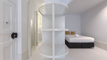 A modern bedroom with a bed, a white circular shelf unit, and a door with a lock.