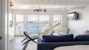 A room with a large window, a sofa, a chair, and a fish decoration on the ceiling. - Stay at Rocky Neck (Gloucester)