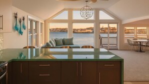 A spacious kitchen with a large island, a dining area with a view of the water, and a cozy seating area with a view of the cityscape. - Stay at Rocky Neck (Gloucester)