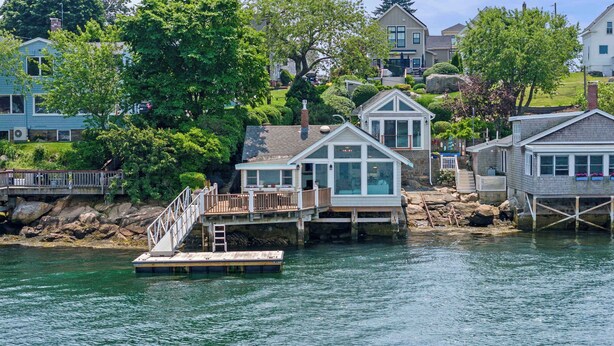 A waterfront property with a dock, a small house with a balcony, and a larger house with a garage. - Stay at Rocky Neck (Gloucester)
