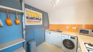 A compact kitchen with a washing machine, a sink, and a microwave. - Airy one-bed in Limehouse with views of the city (London)