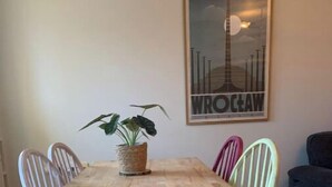 A dining table with six chairs, a potted plant, and a framed poster on the wall. - Airy one-bed in Limehouse with views of the city (London)