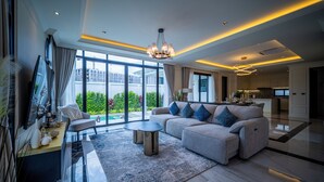 A modern living room with a sofa, coffee table, and TV. - FIFTH ELEMENT pool villa by NLA (Choeng Thale)