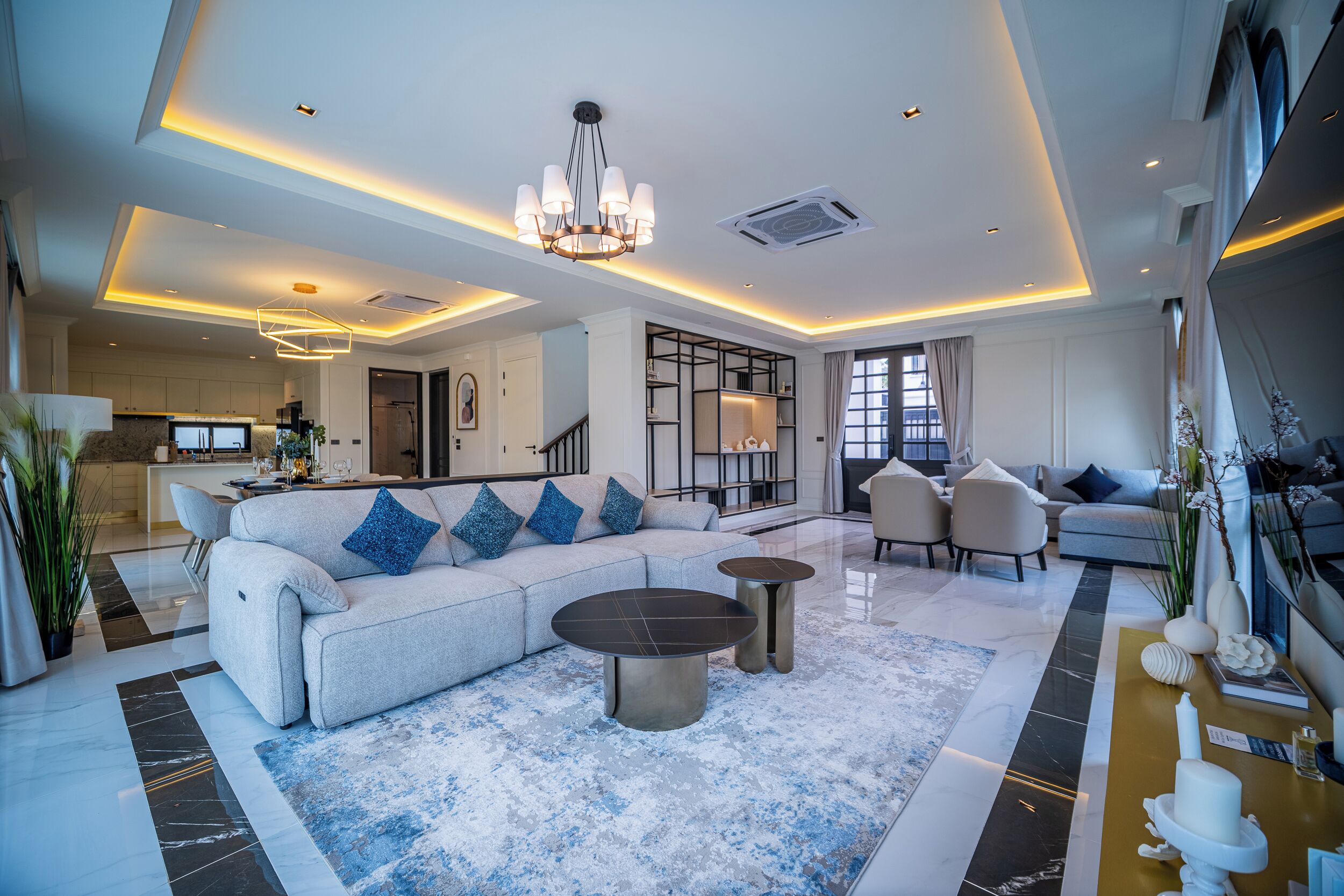 A spacious living area with a large sofa, two side tables, and a chandelier.