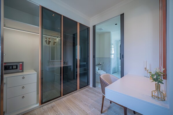 Une salle de bain moderne avec une douche  à parois de verre, un meuble-lavabo blanc orné d’un vase doré et un four à micro-ondes posé sur un meuble.