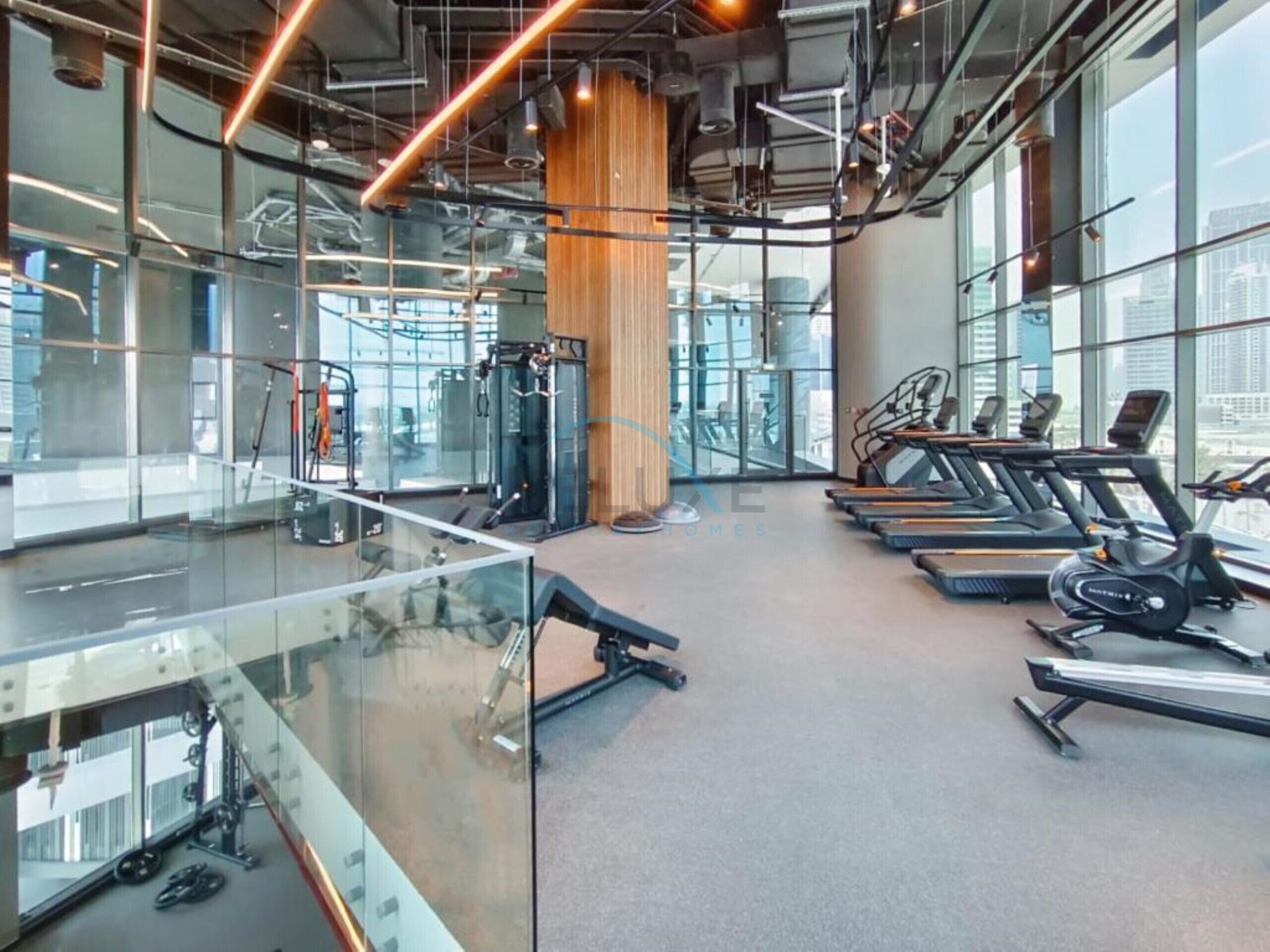 A modern gym with treadmills, weight machines, and a glass wall overlooking a cityscape.