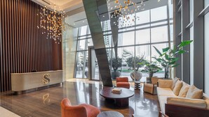 A spacious lobby with a reception desk, seating area, and large windows offering views of the city. - StayShort - 3 Bedroom Apartment in Sterling West with Full Burj Khalifa Views (Business Bay)