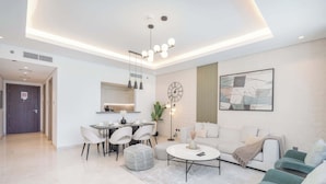 A modern living room with a sofa, a coffee table, and a dining area with chairs and a table. - StayShort - 3 Bedroom Apartment in Sterling West with Full Burj Khalifa Views (Business Bay)