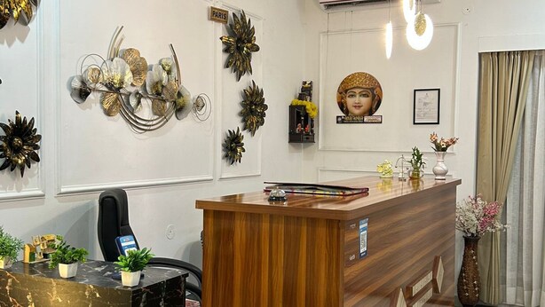 A reception area with a wooden reception desk, a black marble counter, and decorative wall clocks labeled 'LONDON', 'INDIA', and 'PARIS'. - PURPLE PETAL HOTEL (Rohtak)