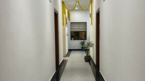 A hallway with white walls, a black and white tiled floor, and yellow garlands hanging from the ceiling. - PURPLE PETAL HOTEL (Rohtak)