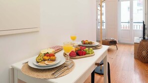 A breakfast table with plates of food, a glass of orange juice, and a clock on the wall. - Stylish Retreat in Porto's Heart by HostWise (Porto)