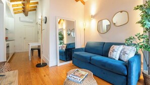 A cozy living room with a blue sofa, a round coffee table, and a mirror on the wall. - Stylish Retreat in Porto's Heart by HostWise (Porto)