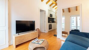 A modern living room with a flat-screen TV, wooden entertainment unit, and a blue sofa. - Stylish Retreat in Porto's Heart by HostWise (Porto)
