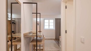 A modern hotel room with a wooden dining table, a large mirror, and a view of the outside through a window. - 5 Fervença Boutique Palace Flats by HostWise (Vila Nova de Gaia)