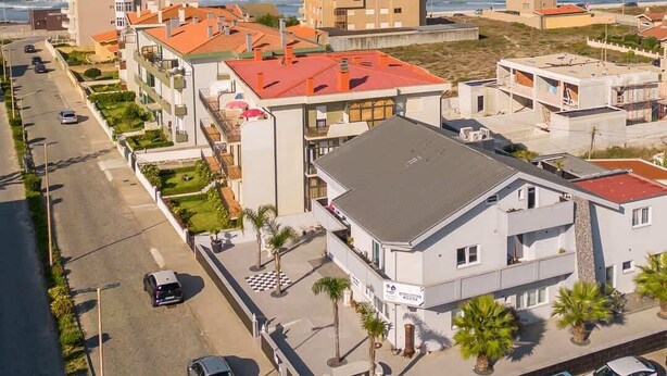 A coastal residential area with modern buildings, a street with parked cars, and a view of the ocean.
