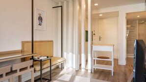 Una sala de estar moderna con una mesa de vidrio, un sofá, una consola blanca y un cuadro en la pared.