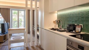 Una cocina moderna con armarios blancos, salpicadero de azulejos verdes y estufa integrada.