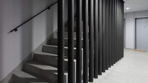 A modern staircase with a metal railing and a carpeted floor.