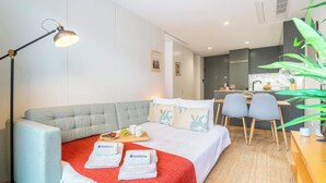 A modern hotel room with a bed, a desk, and a kitchenette.