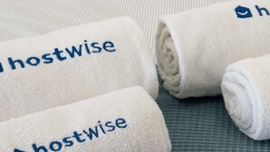 Drei gerollte Handtücher mit dem Schriftzug 'hostwise' und einem Logo auf einer strukturierten Oberfläche.