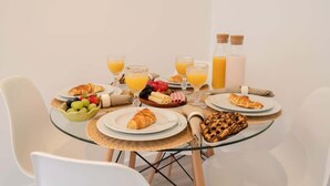 A breakfast setting with croissants, fruit, and orange juice on a glass table. - Trendy Spacious Flat by HostWise (Matosinhos)