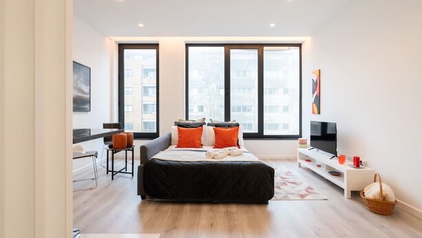 A modern bedroom with a large bed, a desk, and a TV. - Trendy Spacious Flat by HostWise (Matosinhos)