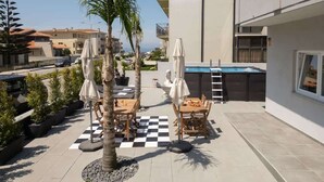 A rooftop patio with outdoor furniture, a pool, and a view of the sea. - Host Wise Arvore - Room w/ Terrace & Pool (Árvore)