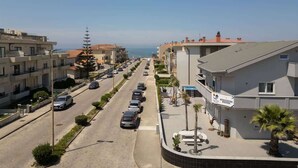 A residential street with parked cars, a clear sky, and buildings with balconies. - Host Wise Arvore - Room w/ Terrace & Pool (Árvore)