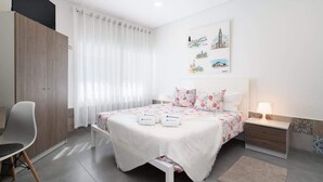 A modern bedroom with a bed, a chair, a nightstand, and a wall with artwork. - Host Wise Arvore - Triple Room w/ Terrace & Pool (Árvore)